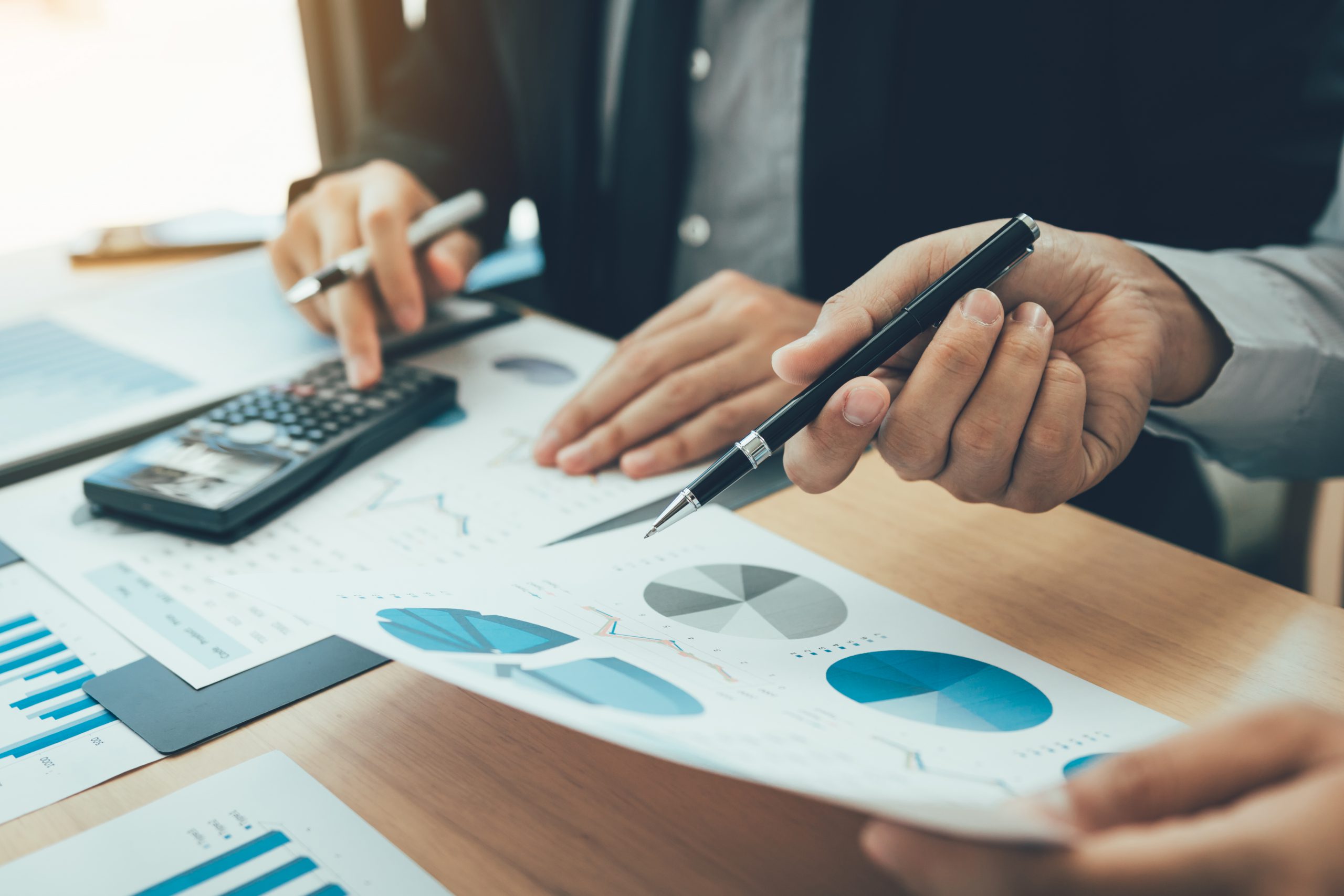 Personas usando calculadora y revisando gráficos sobre el reporte financiero de la empresa.